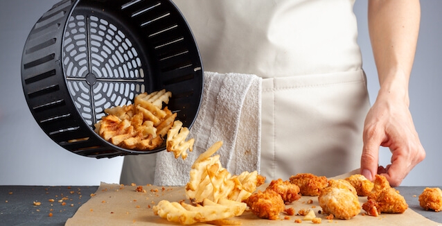 Chef tipping out food from air fryer basket