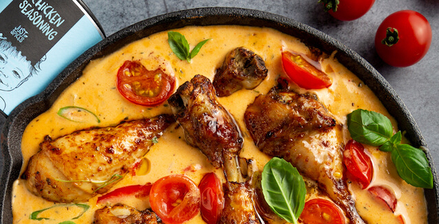Roasted chicken drumsticks in red pepper cream sauce in cast-iron pan