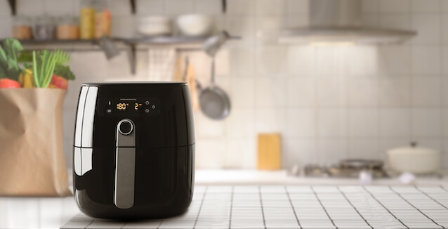 Air fryer in smart kitchen with bag of groceries in background