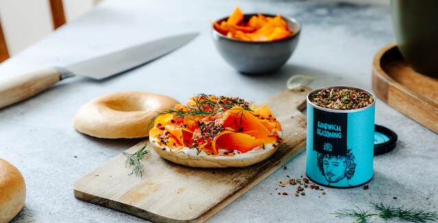 Vegan smoked salmon on bagel on a board with knife and Just Spices Sandwich Seasoning